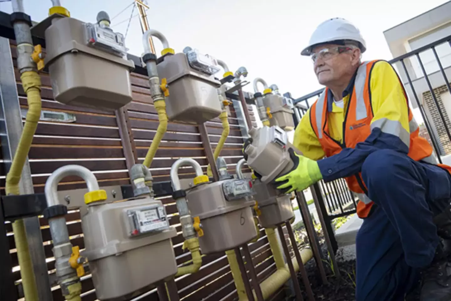 Gas technician in safety gear inspecting and maintaining gas meters.