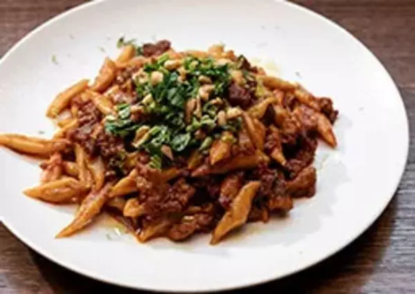 Stir-fried scissor cut noodles dish with meat, vegetables, and sauce on a white plate.