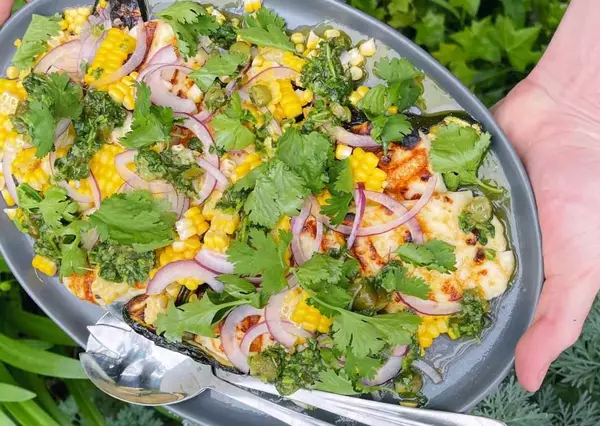 Fresh salad bowl being prepared outdoors with vibrant greens and vegetables.