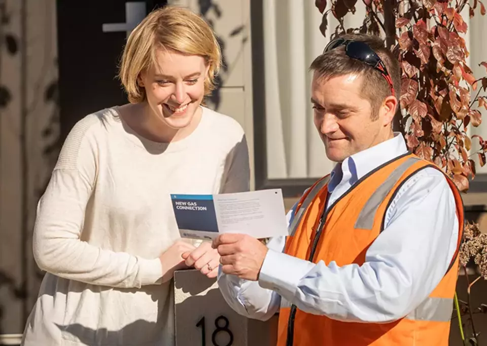 A customer speaking with a gas meter technician outside their home.