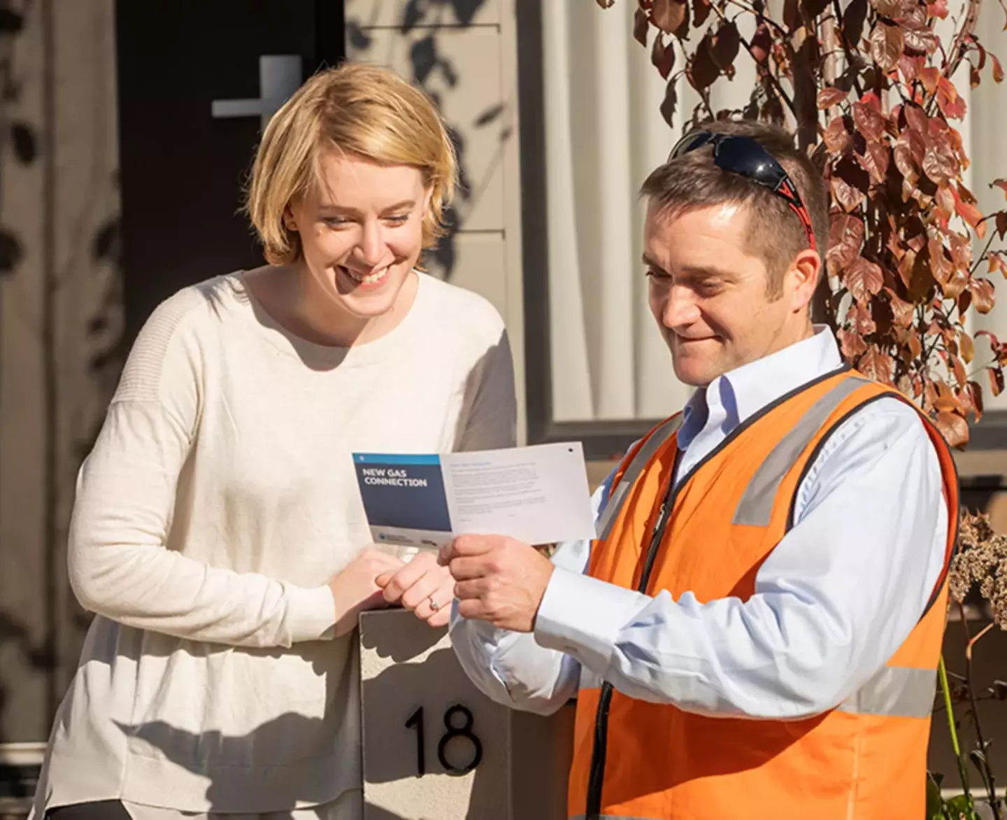 A customer speaking with a gas meter technician outside their home.