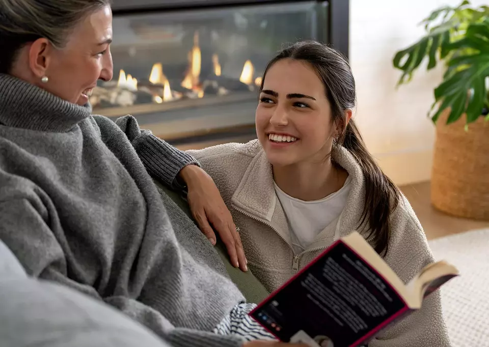 mother and daughter sitting in front of gas fireplace