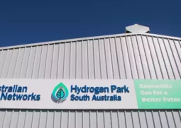 A large sign on an industrial building reads "Australian Gas Networks, Hydrogen Park South Australia, Renewable Gas for a Better Future" under a clear blue sky.