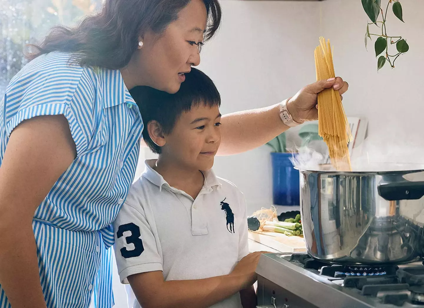 Mother and son cooking pasta with gas cooktop